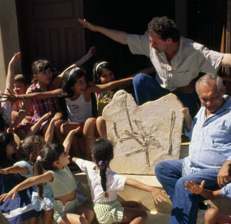 Educators discussing wingspans with students while looking at fossils