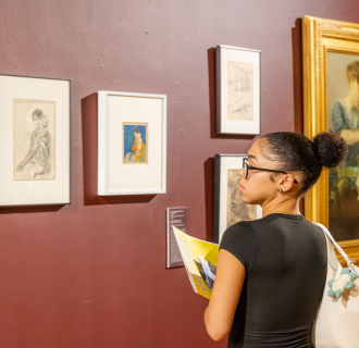 Photograph of student looking at framed artwork by F. Luis Mora