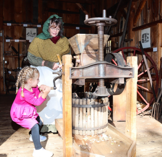 Turning the crank on the antique cider press. 