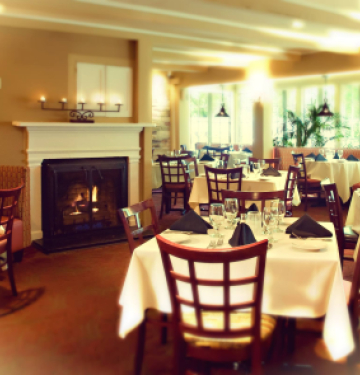 Cozy dining room with fireplace, set tables, and large windows