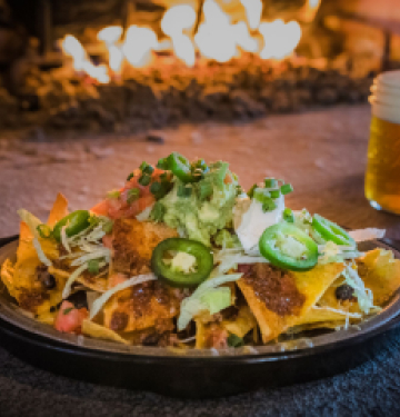 Plate of nachos topped with jalape√±os, guacamole, sour cream, and green onions
