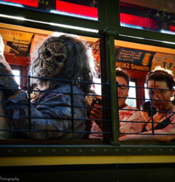 People in gruesome zombie costumes sitting inside a trolley car