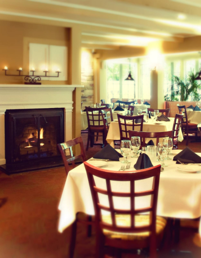 Cozy dining room with fireplace, set tables, and large windows