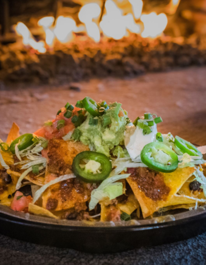 Plate of nachos topped with jalape√±os, guacamole, sour cream, and green onions