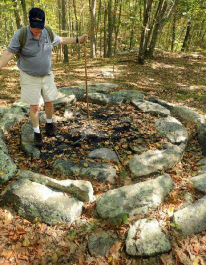Man standing in center of circle of stones in a forest