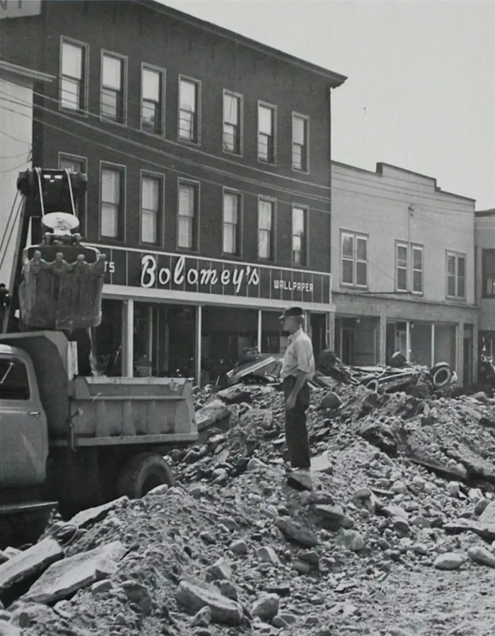 Historical photo of the town of winsted with rubble and deposits piled up in the streets following the flood of 1955.