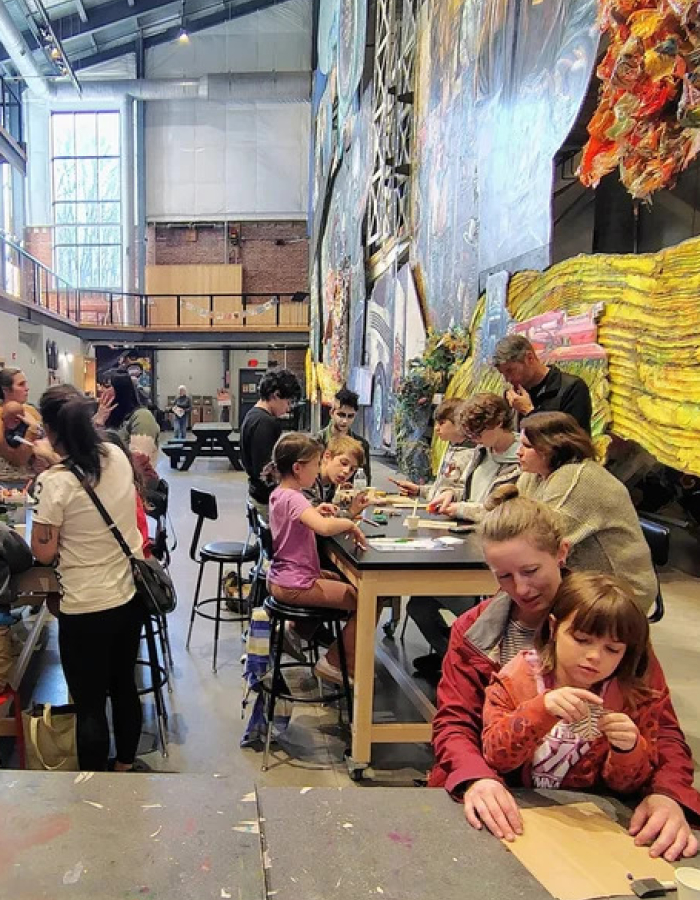A crowd of various families doing arts and crafts together in a large open space.