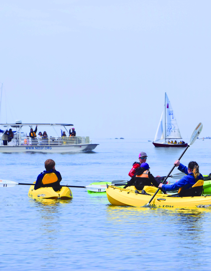 A school group experiences a rotation of three classes: kayaking, on-the-water water quality lab testing, and sailing