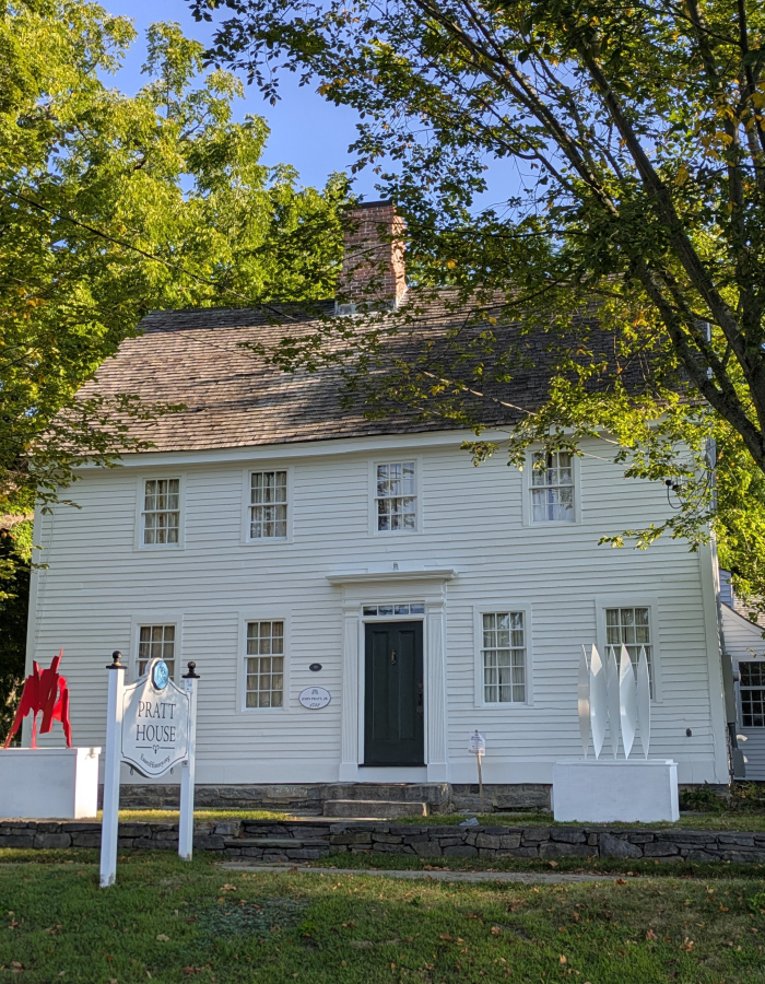 Pratt House in summer with leafy trees and modern art on display