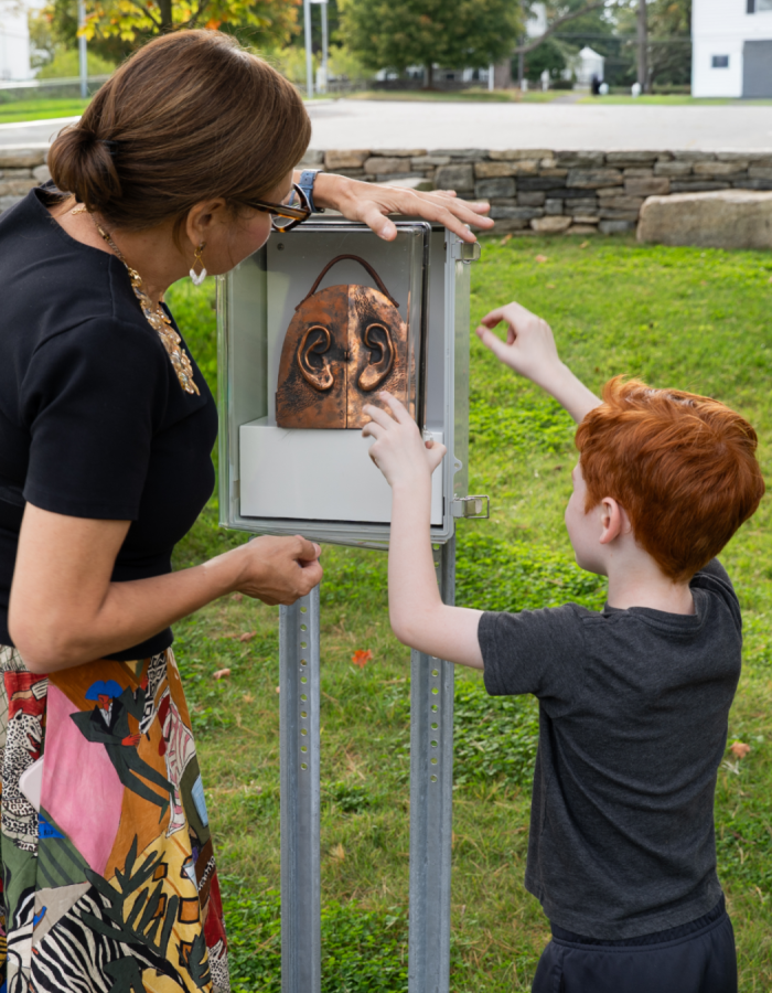 A woman and young boy opening a box with an artwork outside in the Museum's Sculpture Garden