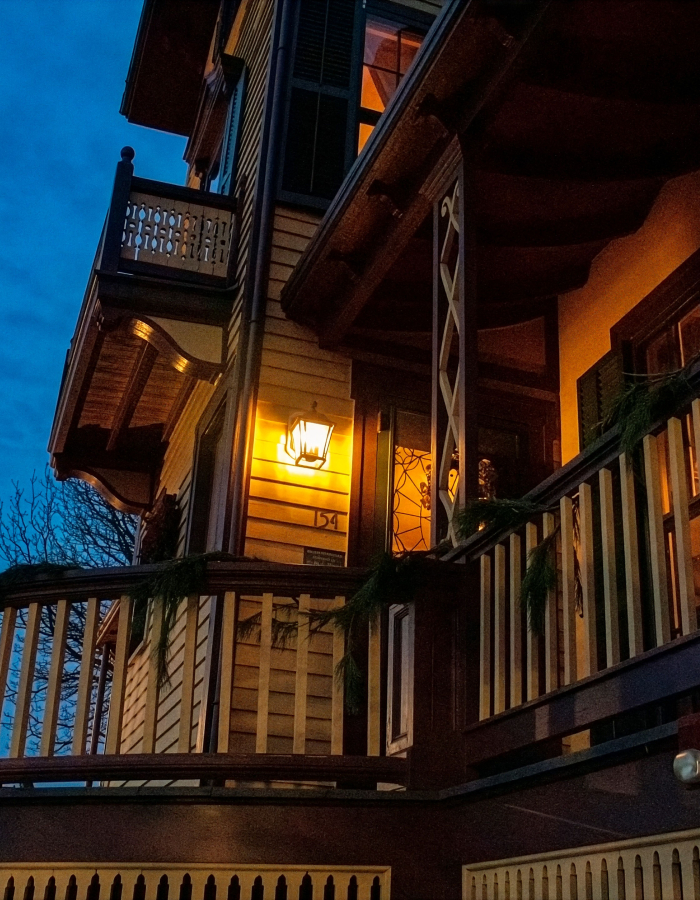 Victorian home at dusk glowing with warm lights, creating an eerie setting for a Haunted Harbor Tour. 