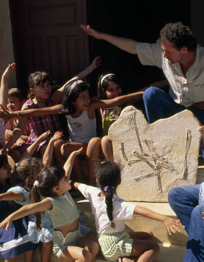Educators discussing wingspans with students while looking at fossils
