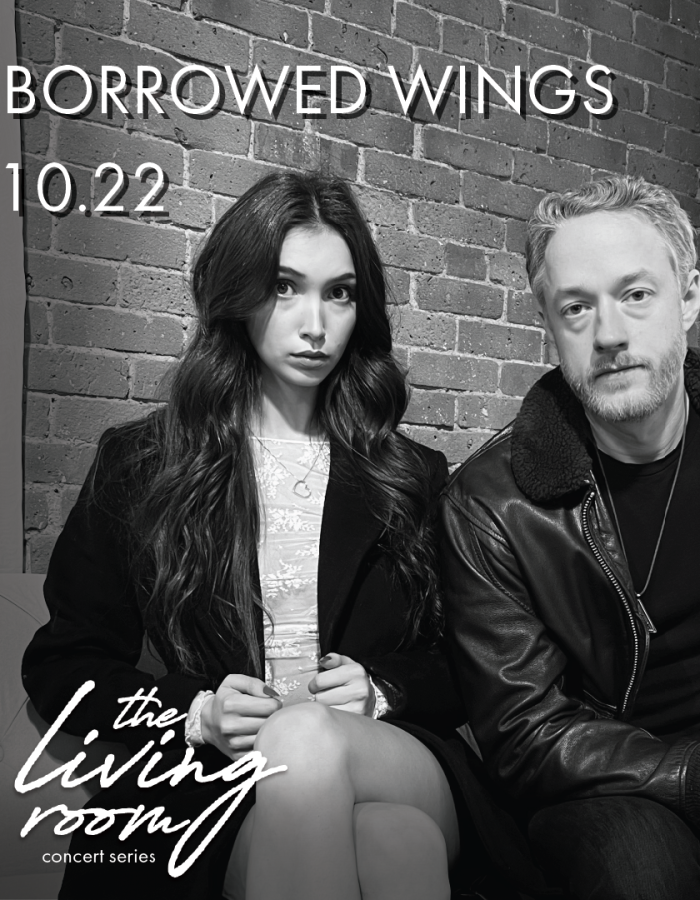 A man and a woman sitting next to each other in front of a brick wall.