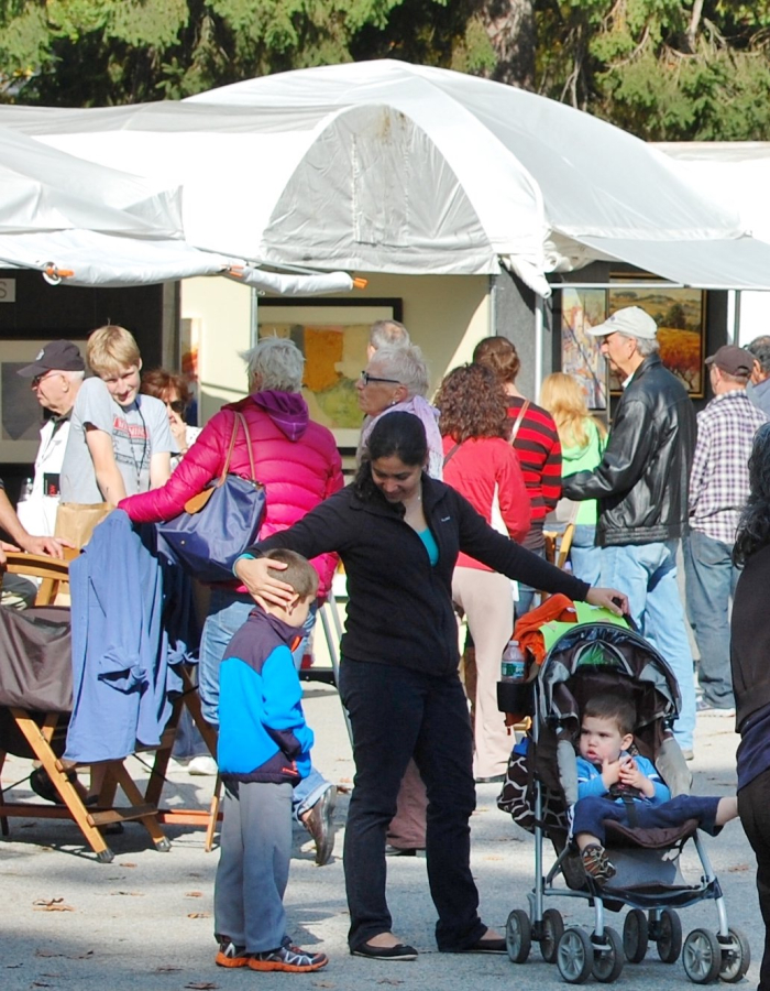 People milling about at an arts festival with tents in background.