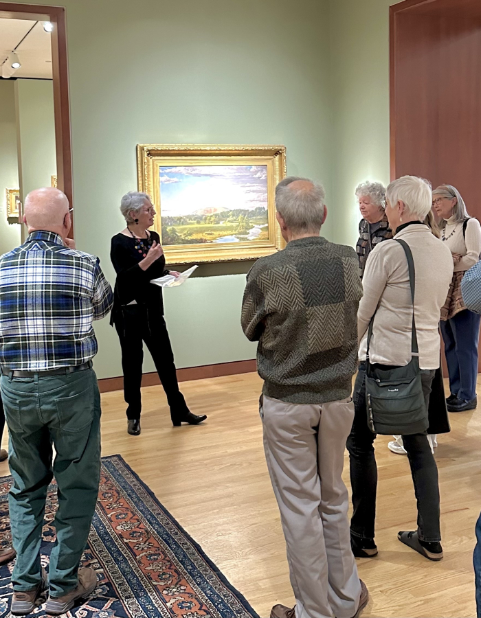 group of visitors in a Museum gallery looking at a landscape painting