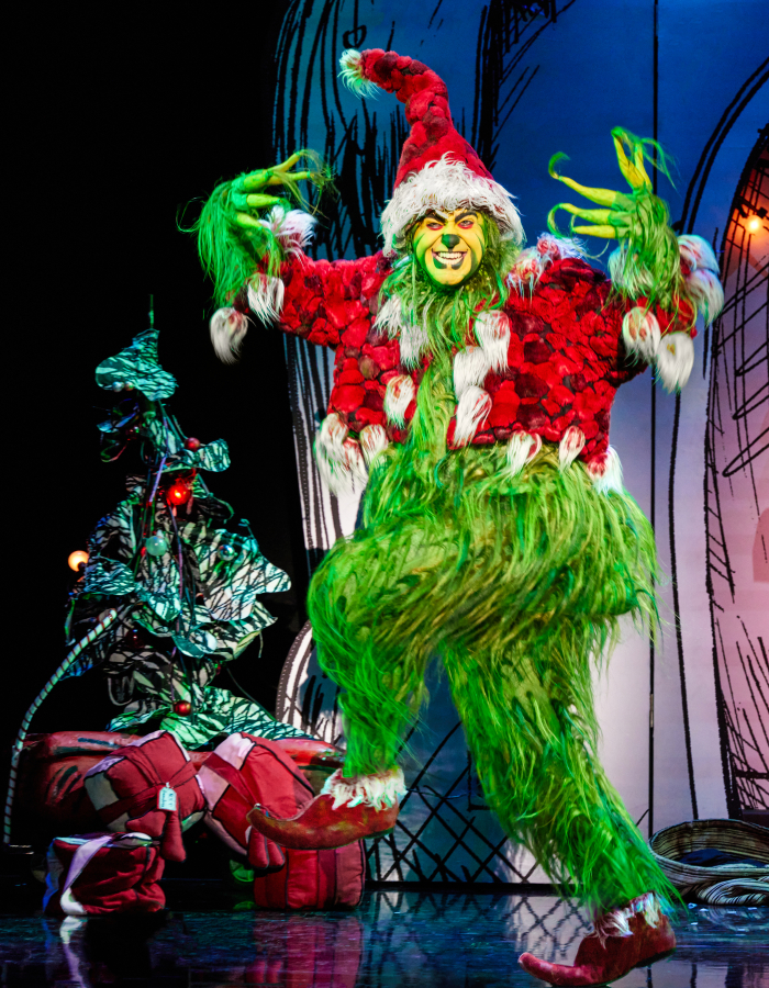 The Grinch wearing Santa clothes with a menacing look on his face.