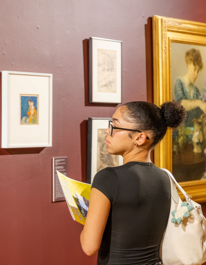 Photograph of student looking at framed artwork by F. Luis Mora