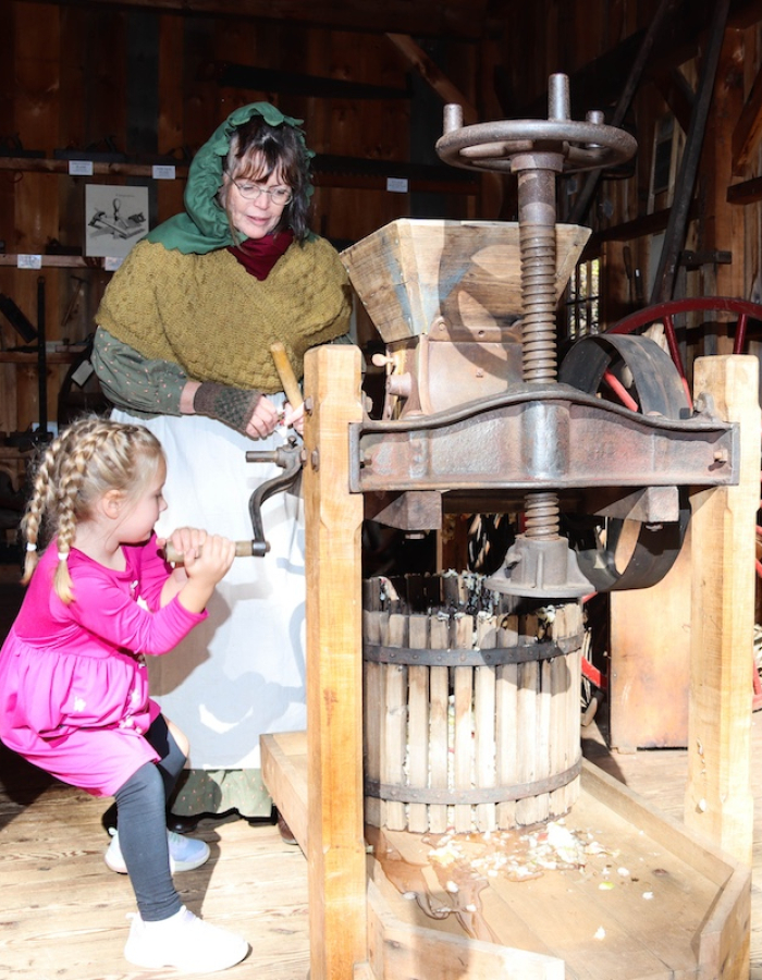 Turning the crank on the antique cider press. 