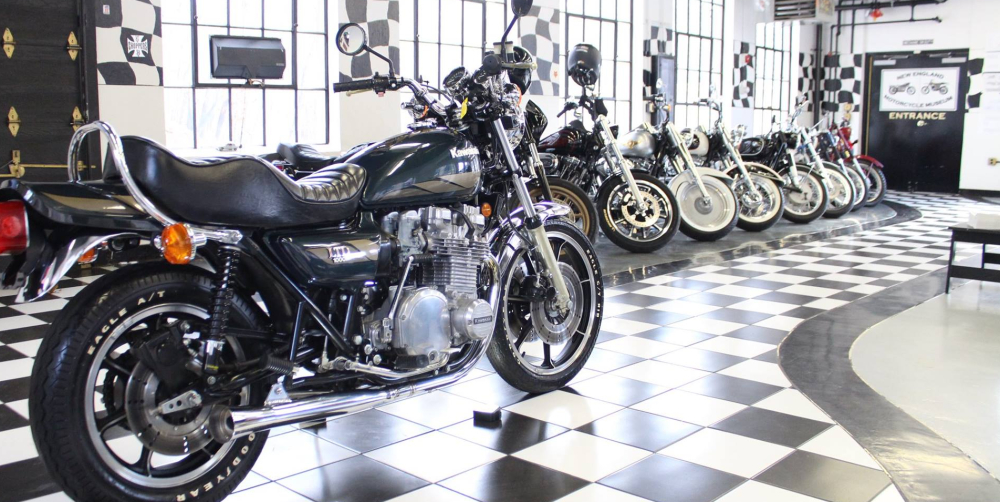 Classic motorcycles displayed on checkered floor in museum showroom