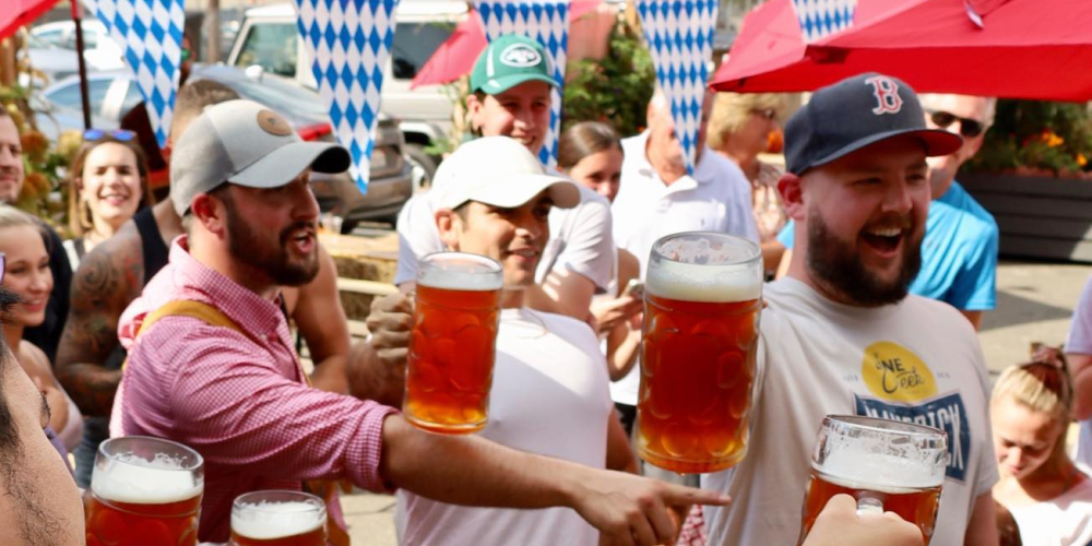 Group of people toasting with large beer mugs at outdoor event