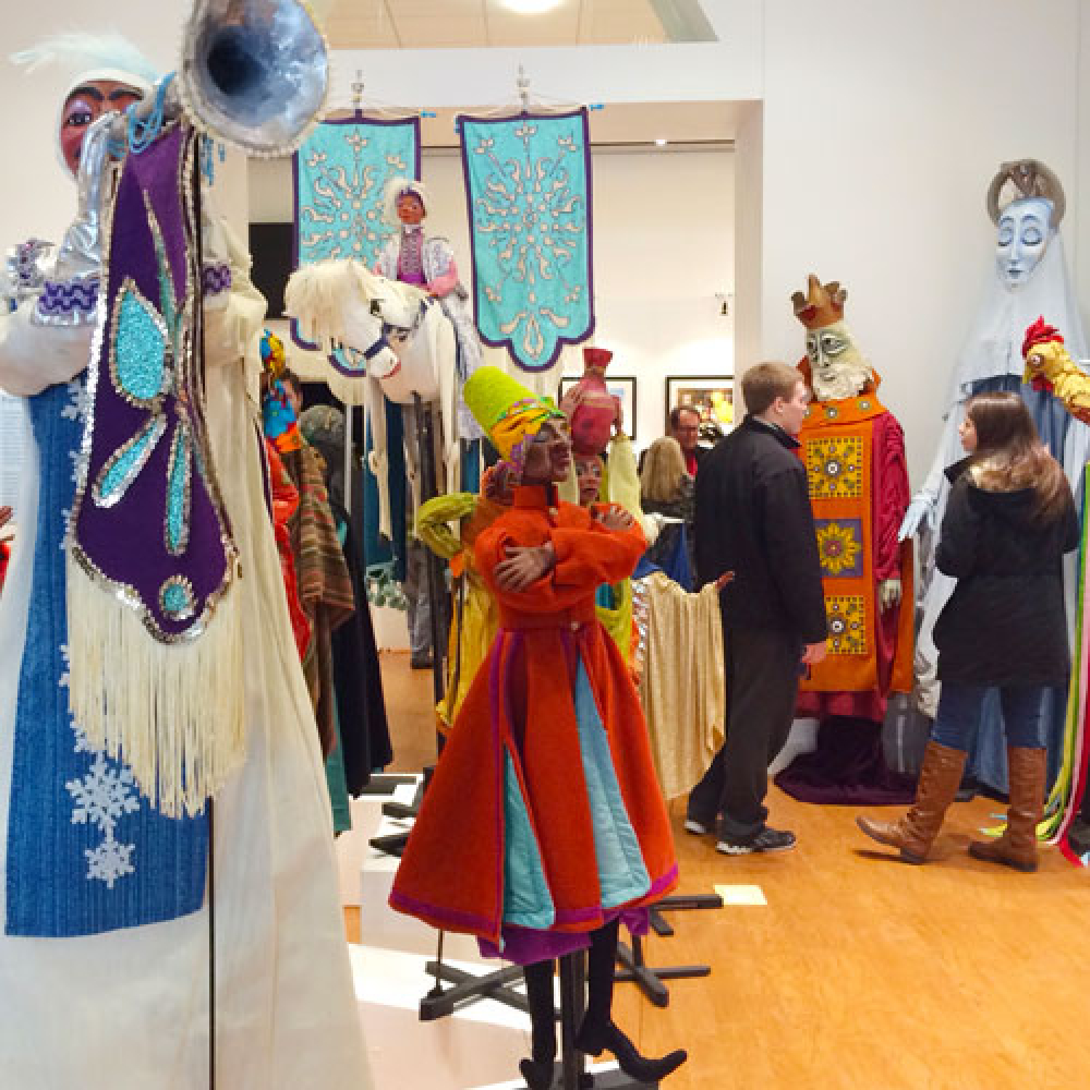 Colorful puppets on display with visitors in a museum setting