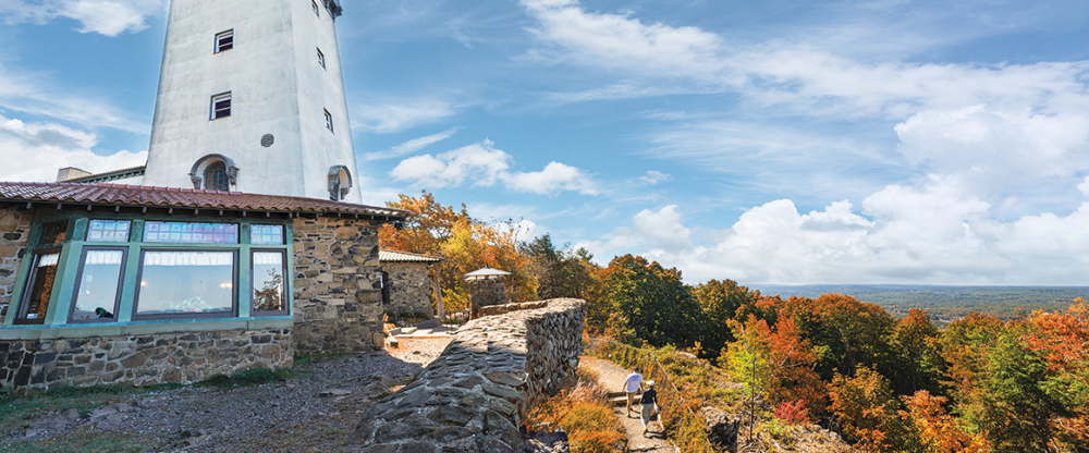 Lighthouse on stone building with autumn trees and walking path