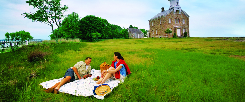 Couple having picnic on grass near historic lighthouse building