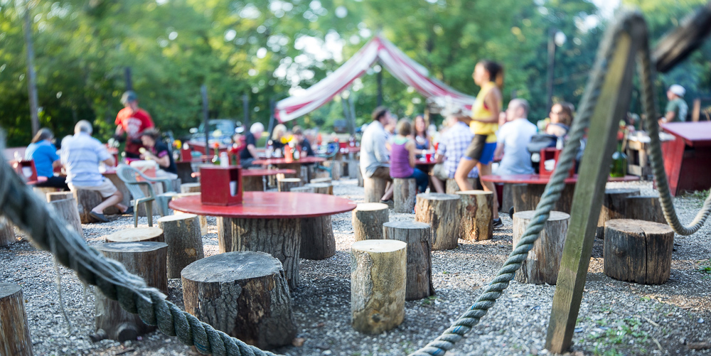 Outdoor seating area with tree stump stools and people socializing