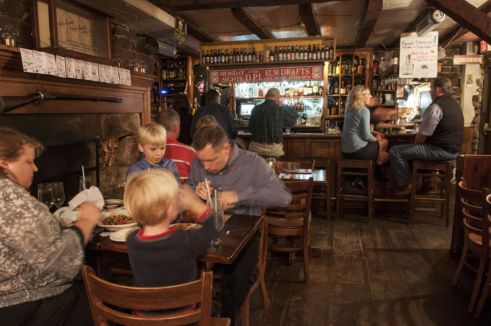 Cozy pub interior with diners at wooden tables and patrons at the bar