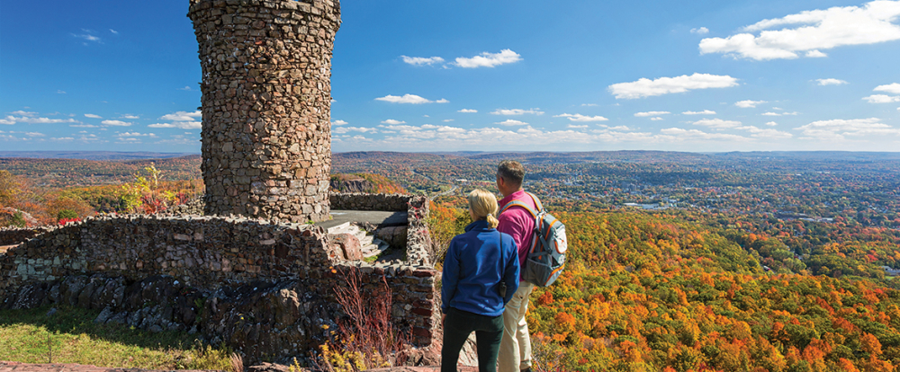 Couple overlooking fall foliage from Castle Craig tower in Connecticut