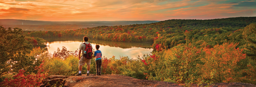 Two people overlooking Crescent Lake and colorful fall foliage at sunset