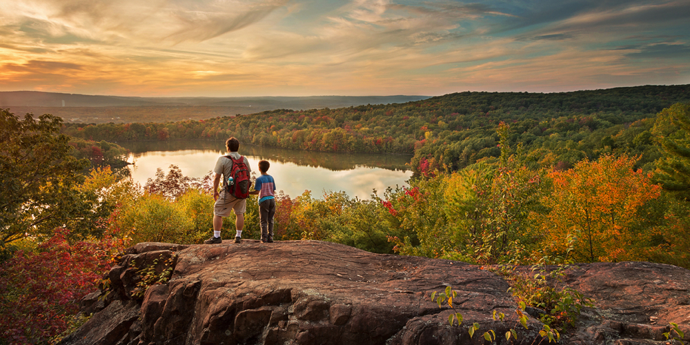 Two hikers overlooking Crescent Lake and autumn forest at sunset