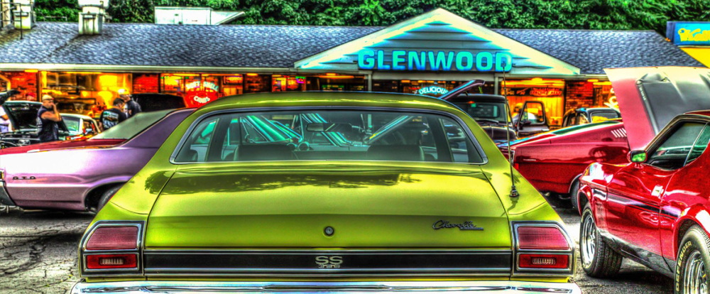 Classic cars parked near Glenwood drive-in restaurant at dusk