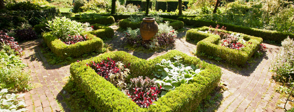 Formal garden with manicured boxwood hedges and central clay urn