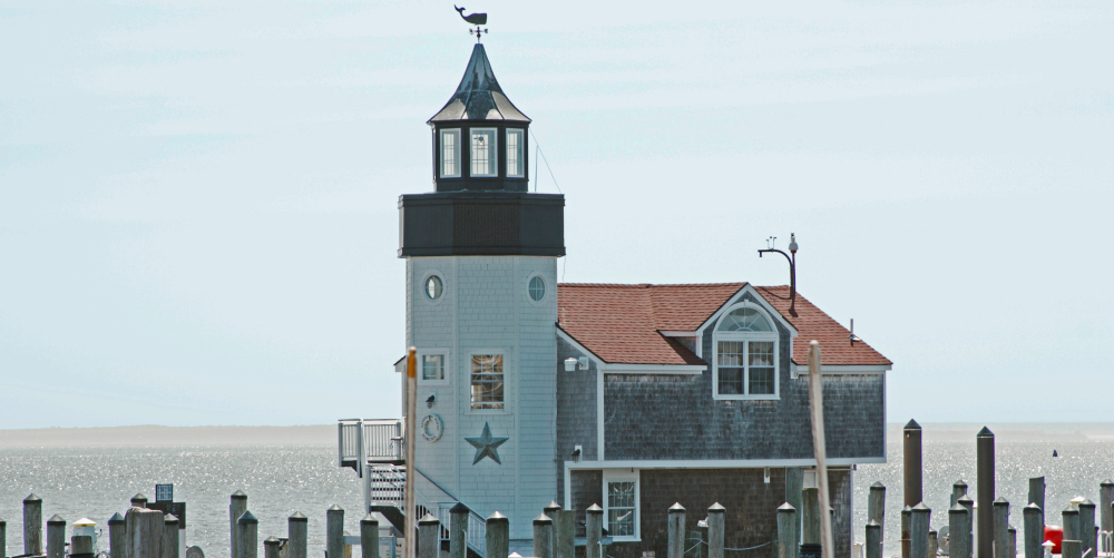 Harbor building with tower and weather vane surrounded by wooden docks