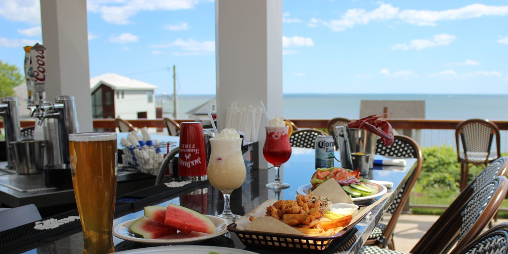 Seafood and drinks on bar counter with ocean view in outdoor dining area