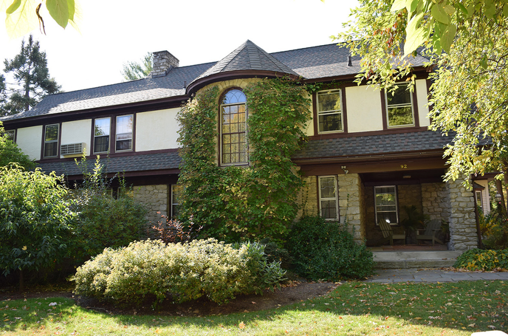 Two-story house with ivy-covered round turret and surrounding greenery