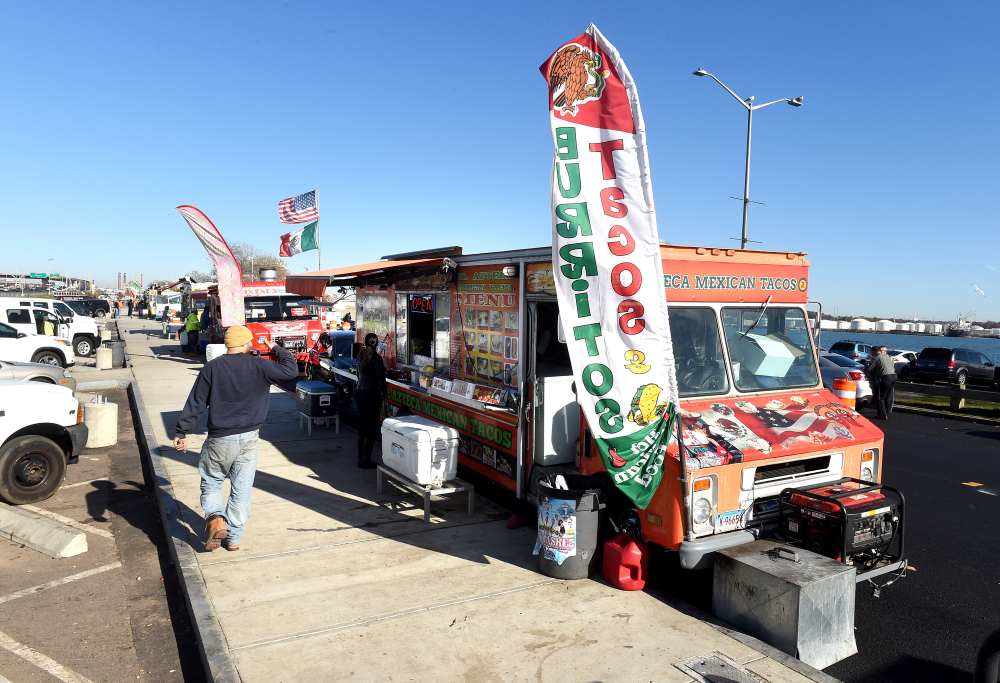 Mexican taco food truck with banners and customers on sunny day