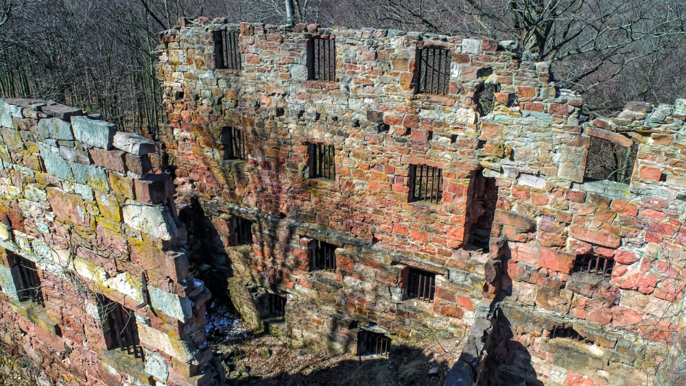 Aerial view of museum Cell Block. A 4-story ruinous structure with only one wall remaining.