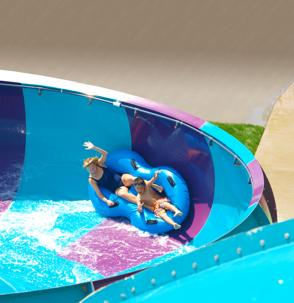 Two people riding a blue raft on a twisting water slide at a water