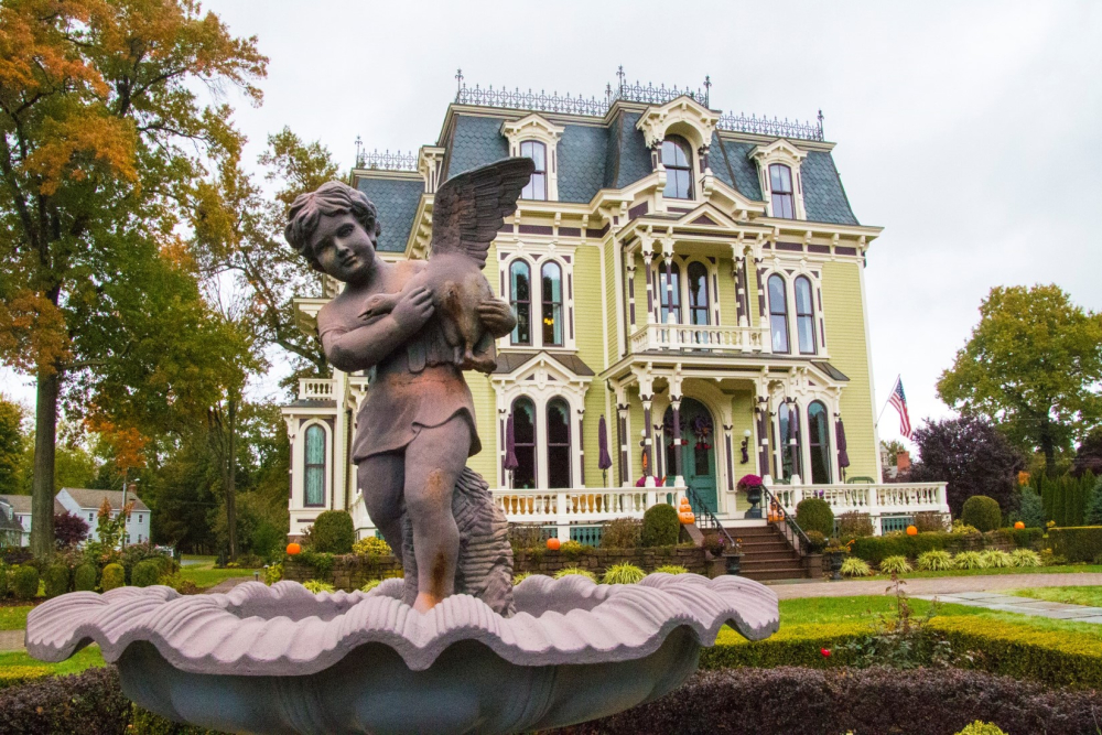 Victorian house with detailed trim and cherub statue fountain in front