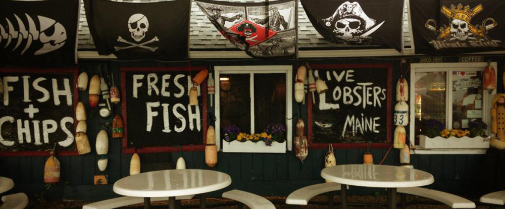 Outdoor seating with seafood signs and pirate flags at Stowe's Seafood
