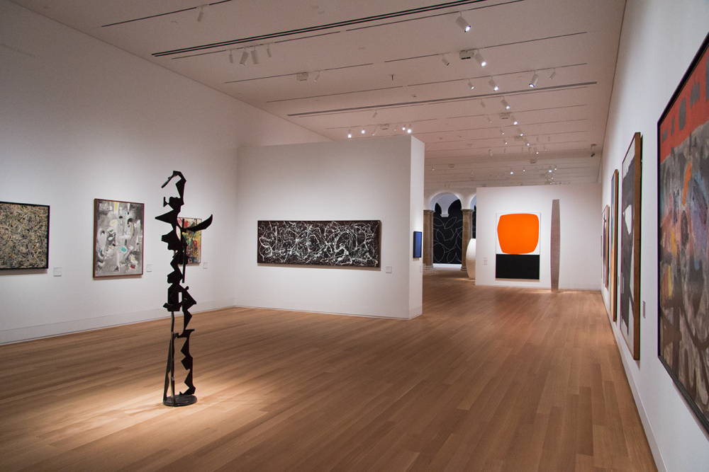 Modern art gallery room with paintings and black abstract sculpture