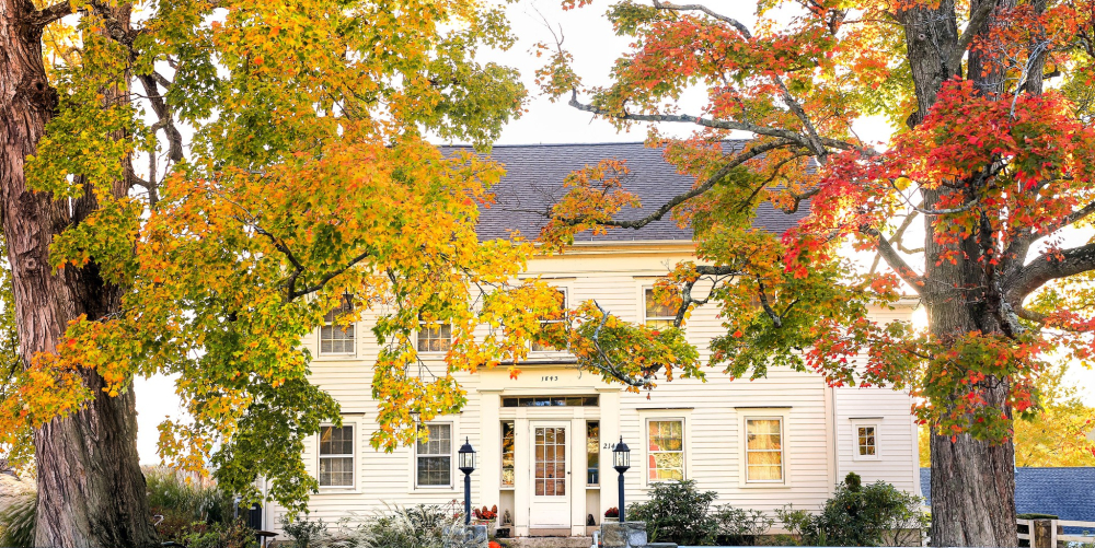 White inn with stone gate and autumn trees with red and yellow leaves