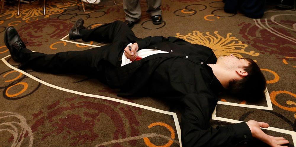 Man lying on floor outlined in chalk, simulating a crime scene