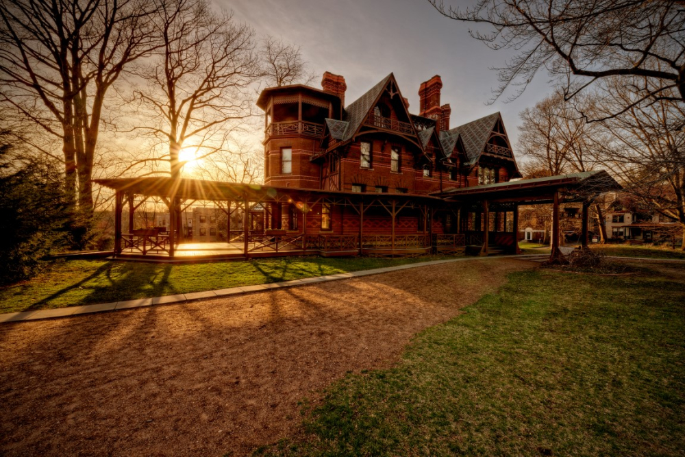 Historic red brick mansion with turret and porch at sunset