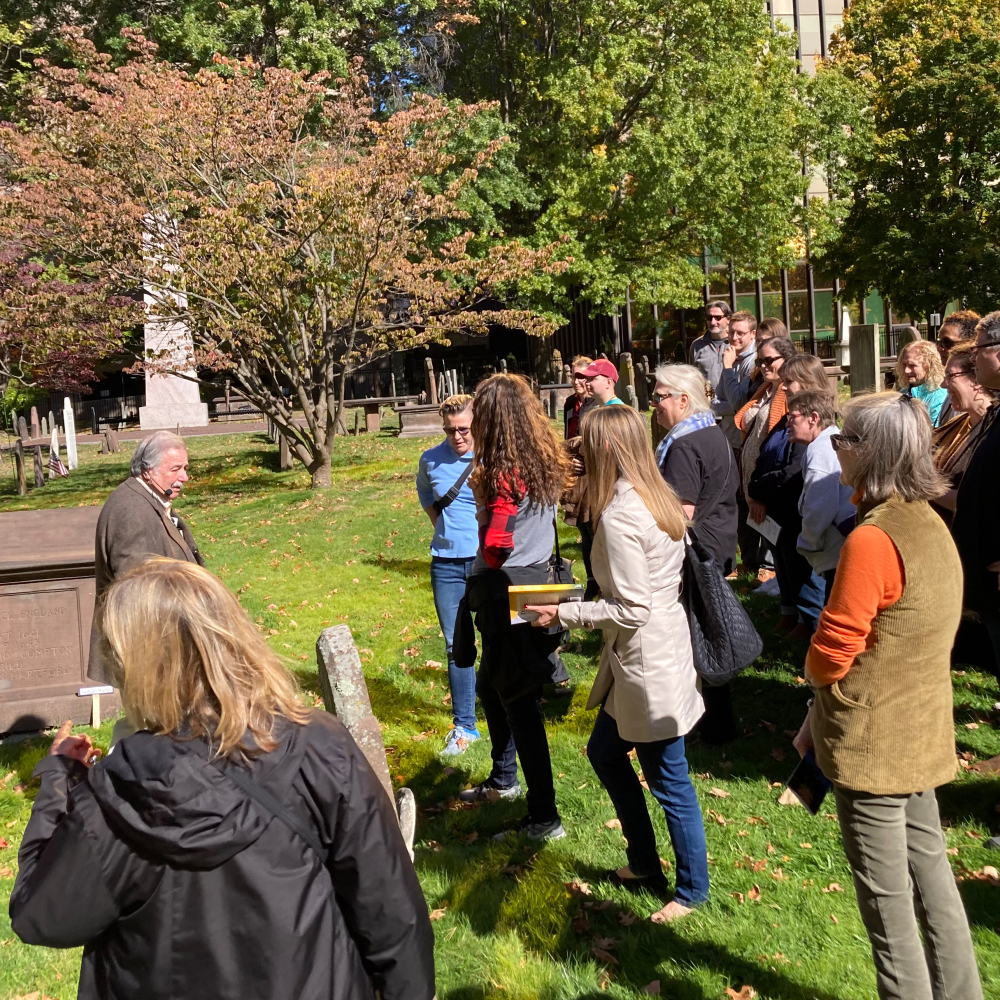 Group touring a historic cemetery with guide speaking near gravestones