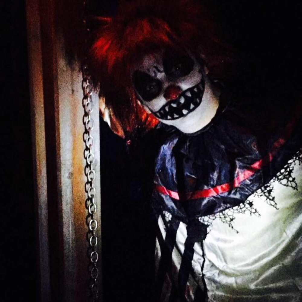 Creepy clown with red hair and sharp-toothed smile in dark setting