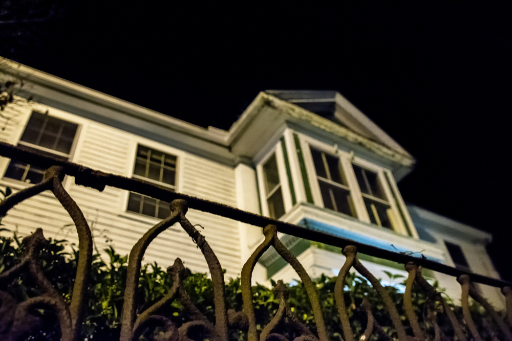 Night view of old house behind wrought iron fence