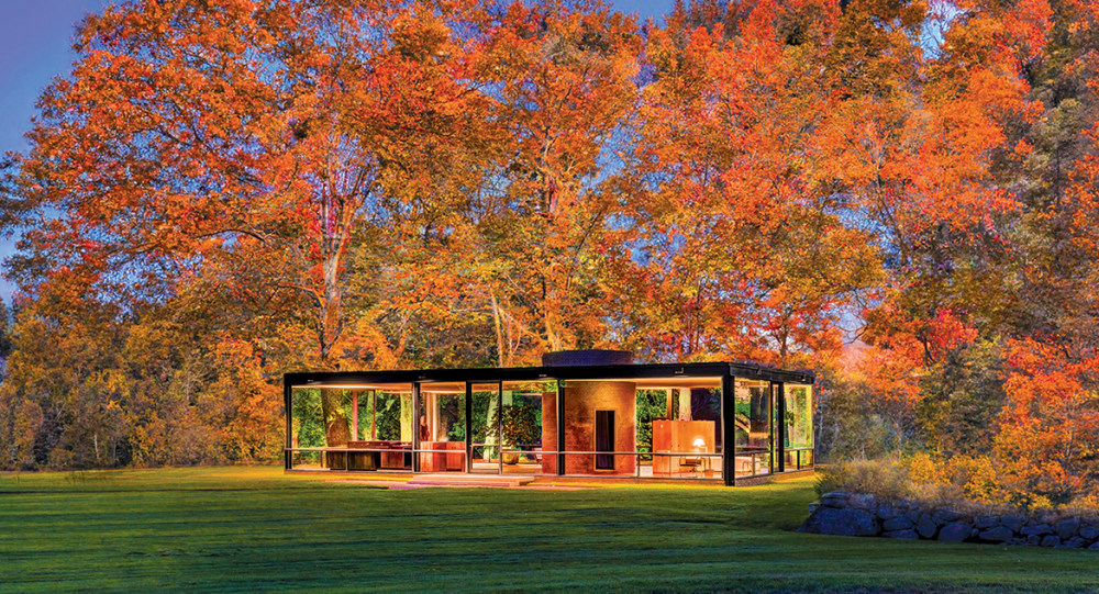 Modern glass house surrounded by vibrant orange autumn trees